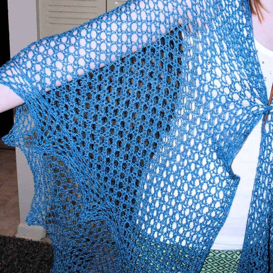 A close up of a blue crochet shawl